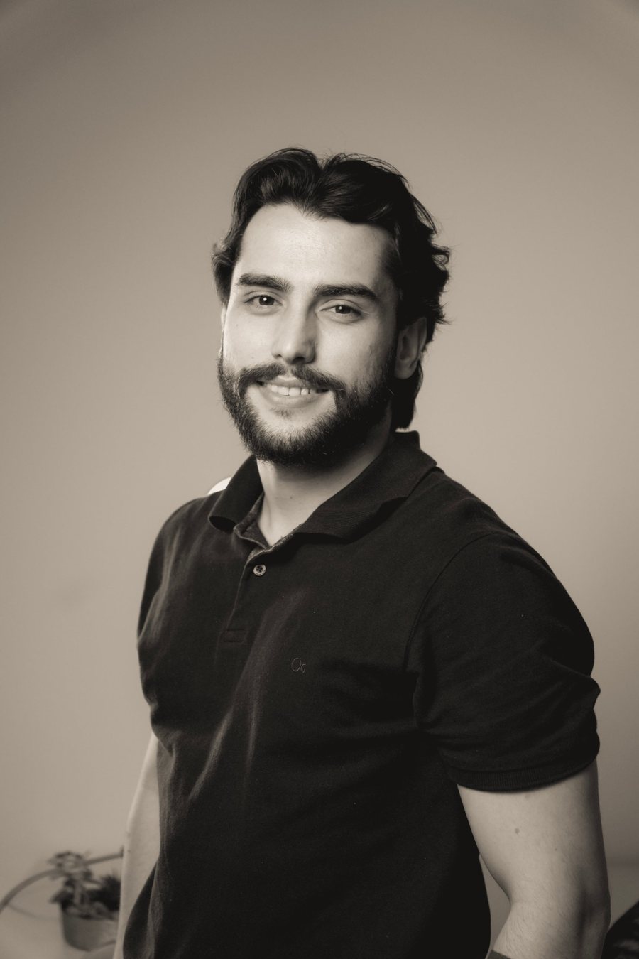 Thiago Maia sorrindo, de camisa polo preta, em retrato em tom sépia